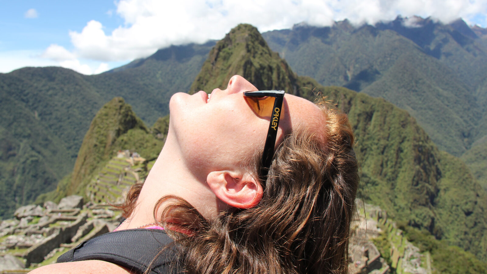 Sarah Ramsey '12 holds turns face up toward the sun, mountains behind her