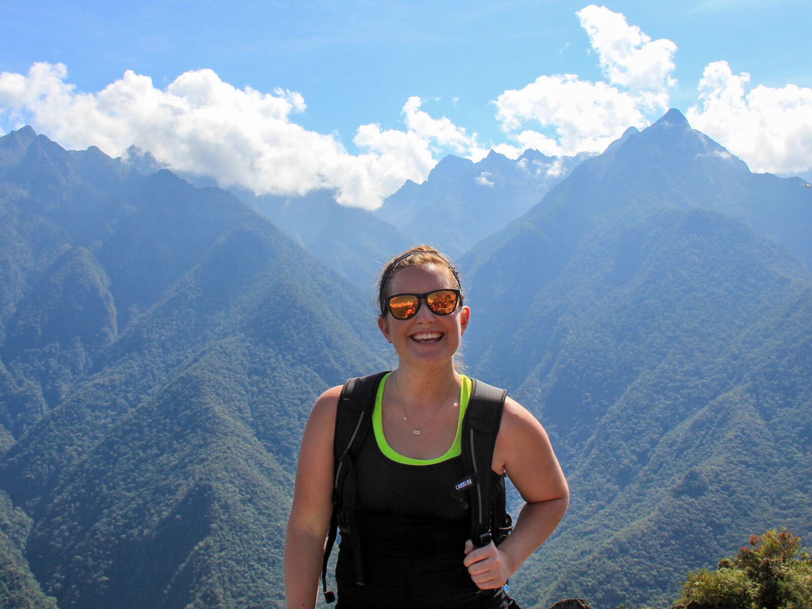 Sarah Ramsey '12 holds backpack, mountains behind her