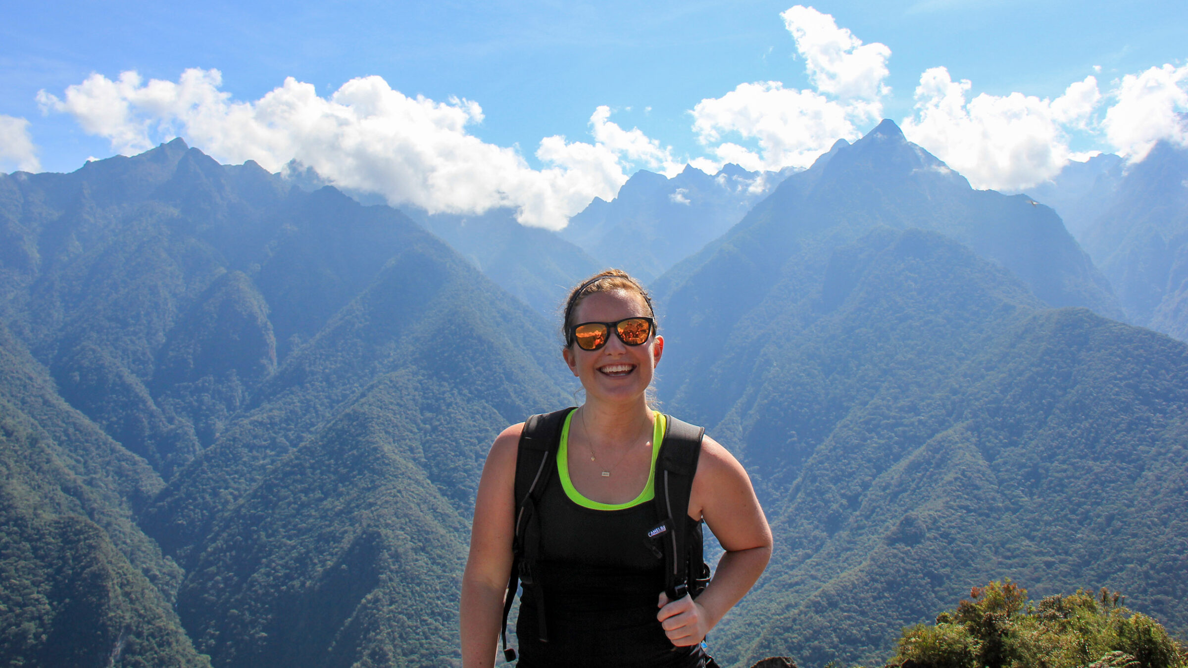 Sarah Ramsey '12 holds backpack, mountains behind her
