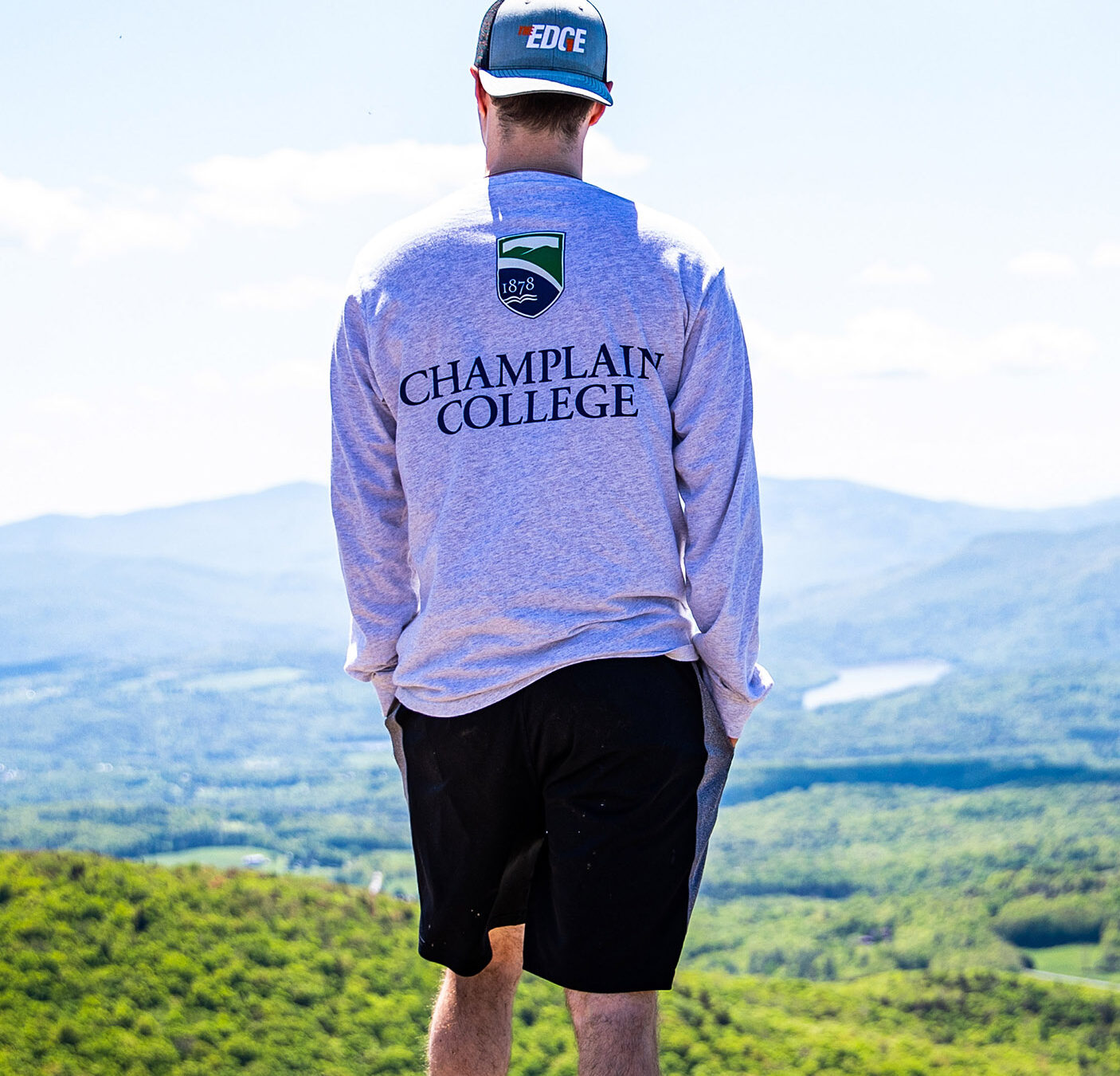 a student in a Champlain t shirt looks out over a vista