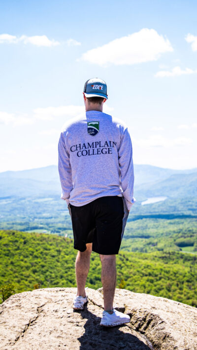 a student in a Champlain t shirt looks out over a vista
