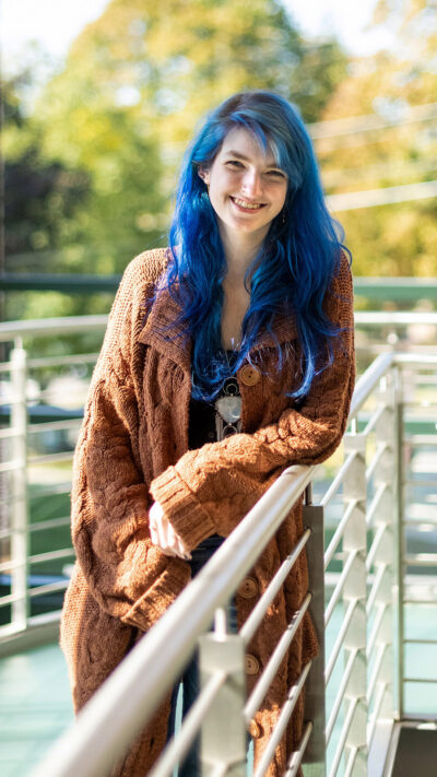 student leans on railings smiles at camera