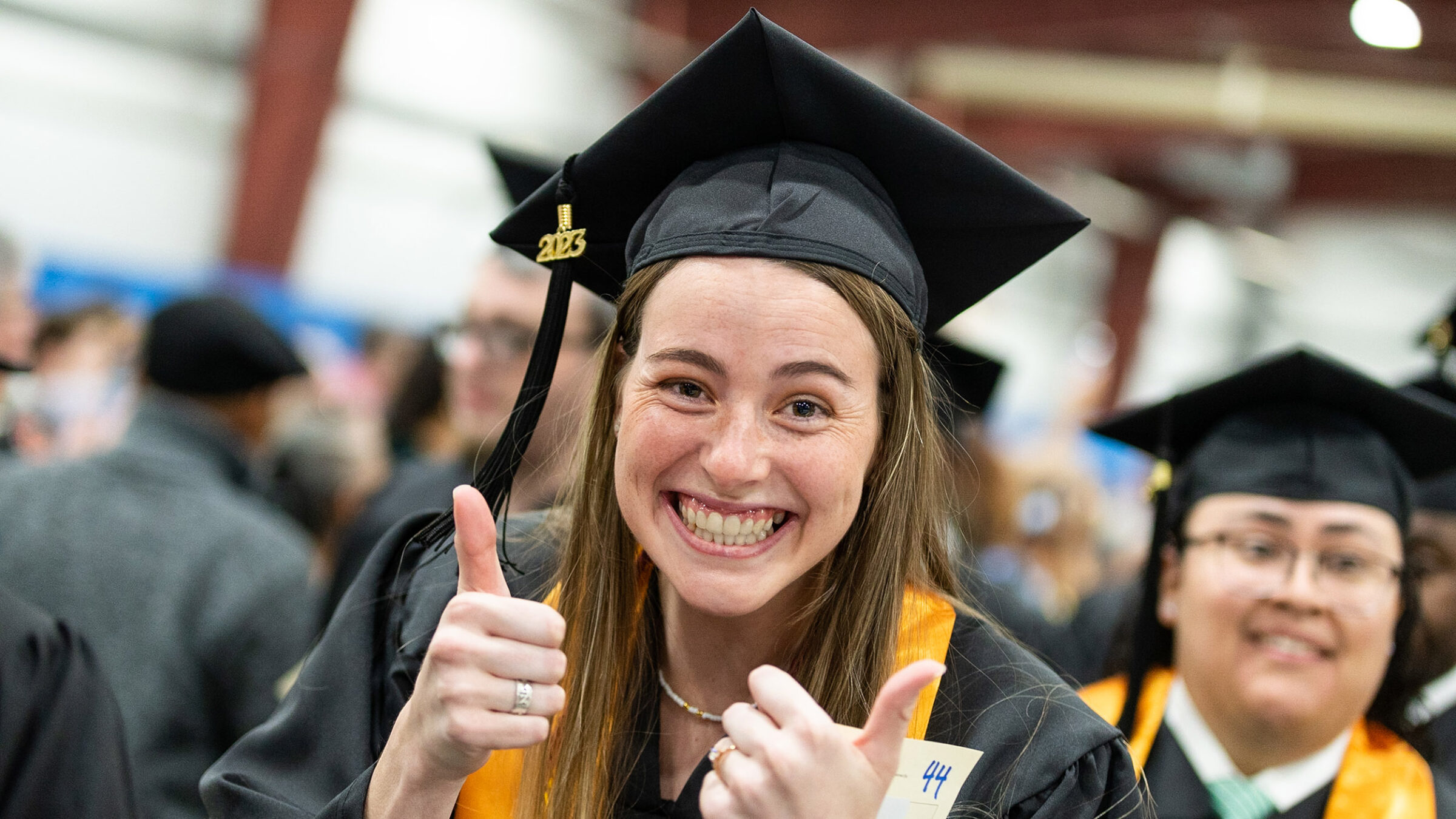 graduate gives the camera a thumbs up during commencement