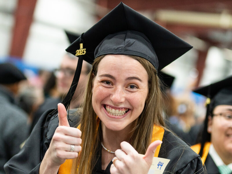 graduate gives the camera a thumbs up during commencement