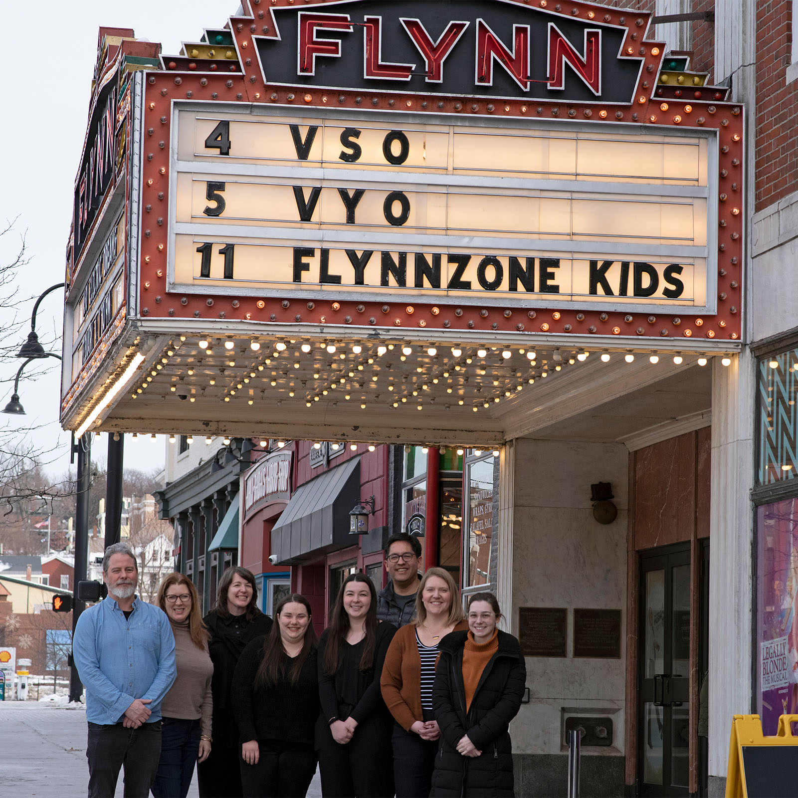 A group of EMC students and employees smile outside of the Flynn for a VSO concert