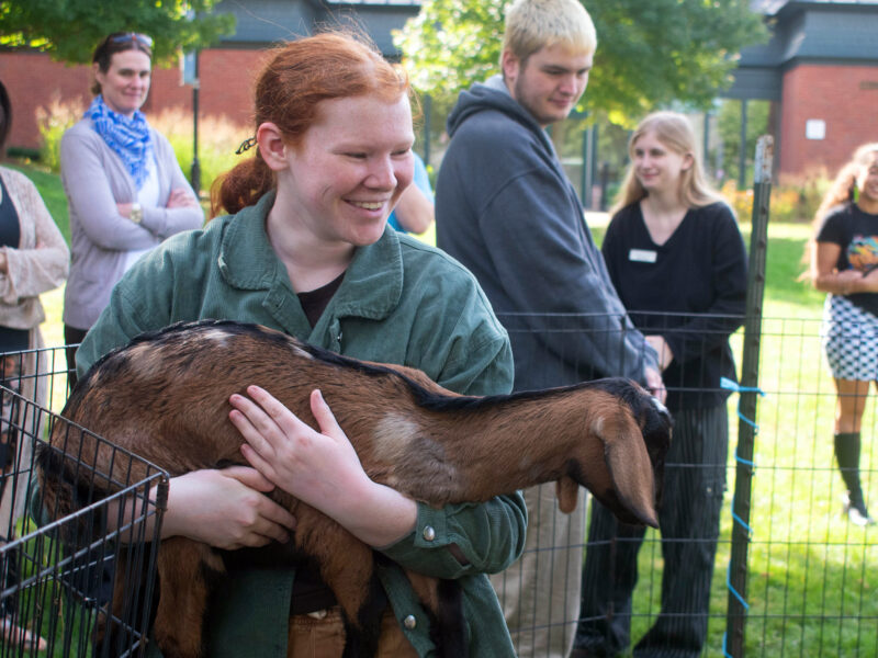 student holds a goat during a de-stress event