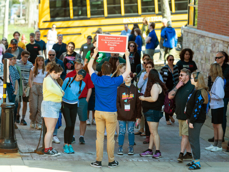Student ambassador holding a sign to direct guests at an Admitted Student Day event
