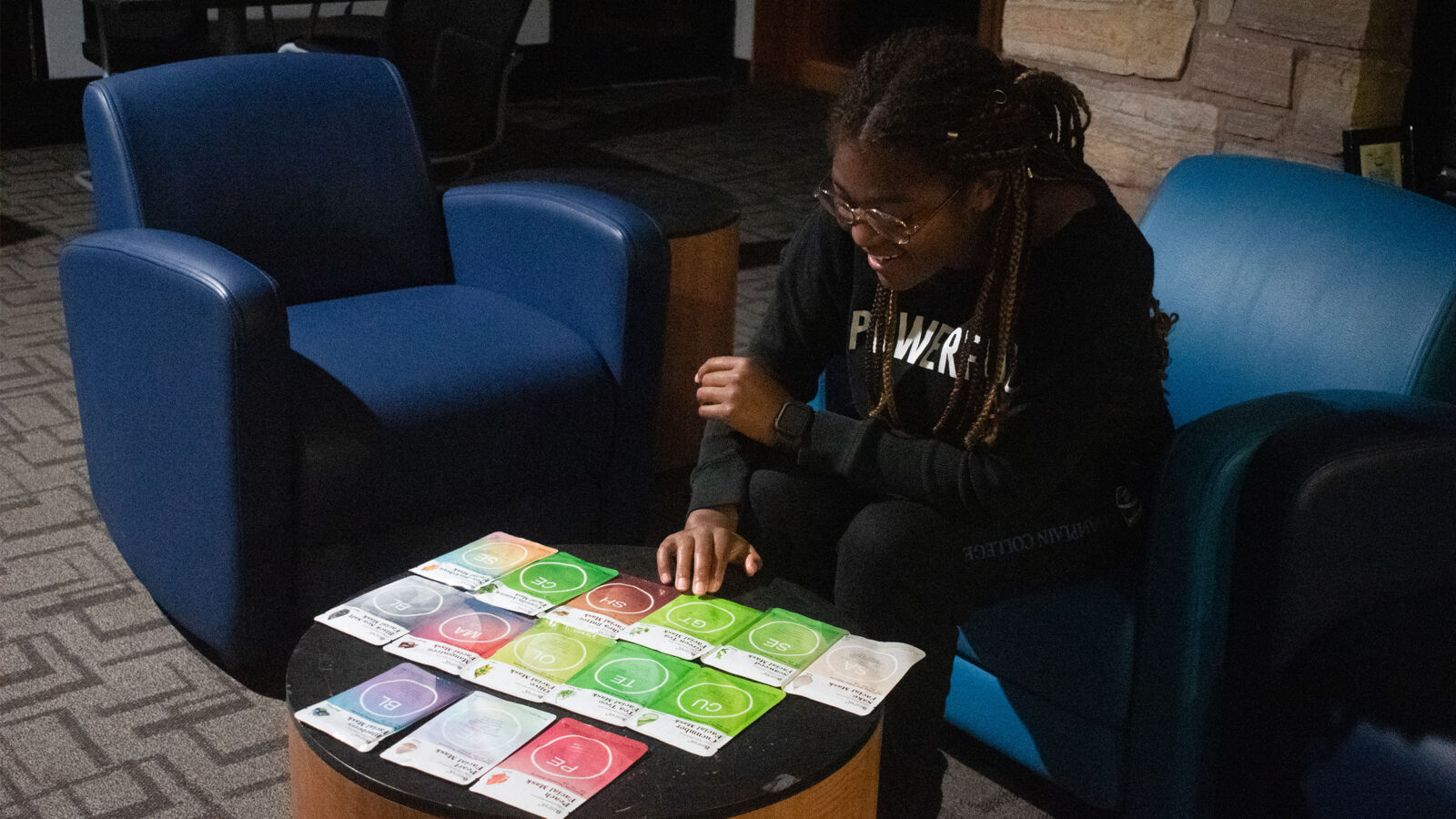 a student reaches for one of a dozen facial masks displayed on a table during a self care night.