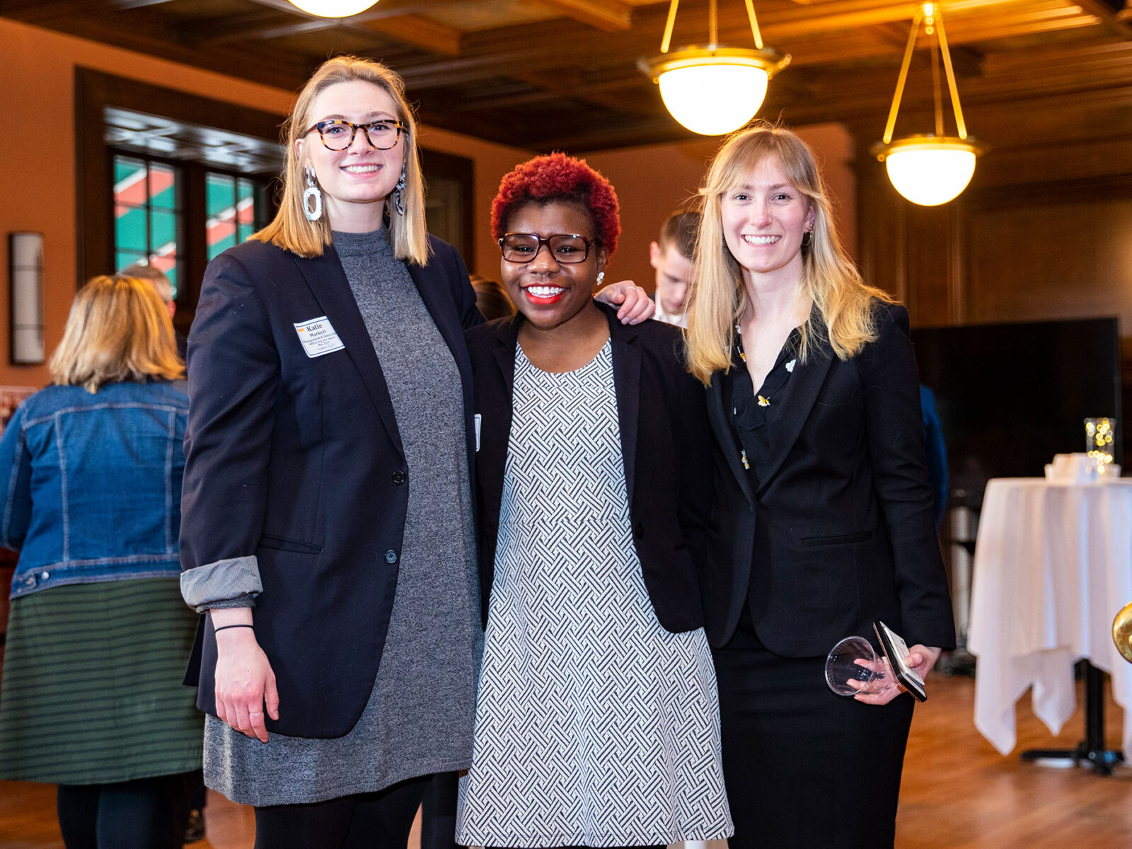 three students stand up posing for a photo with their arms around each other at a networking event
