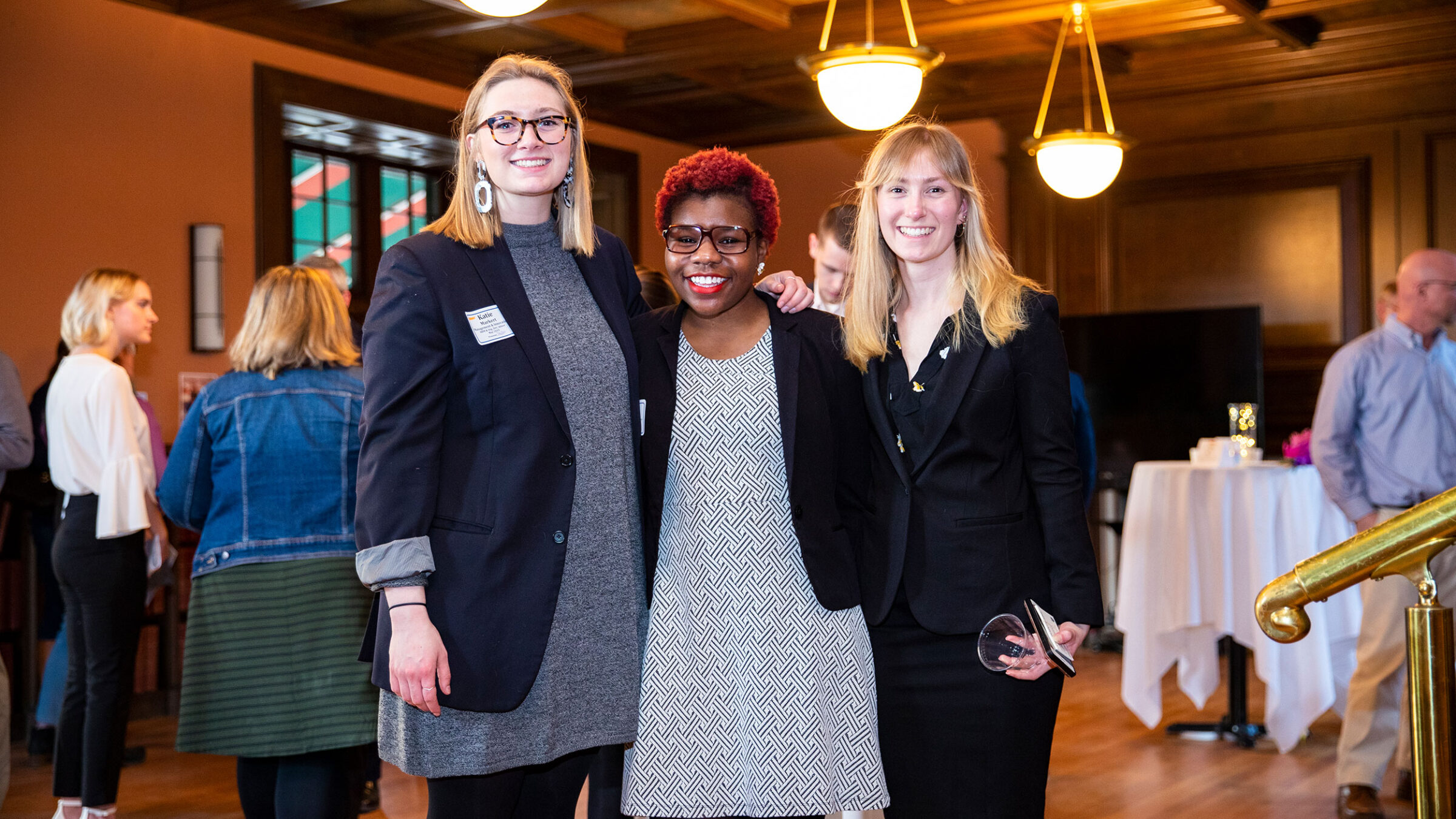three students stand up posing for a photo with their arms around each other at a networking event