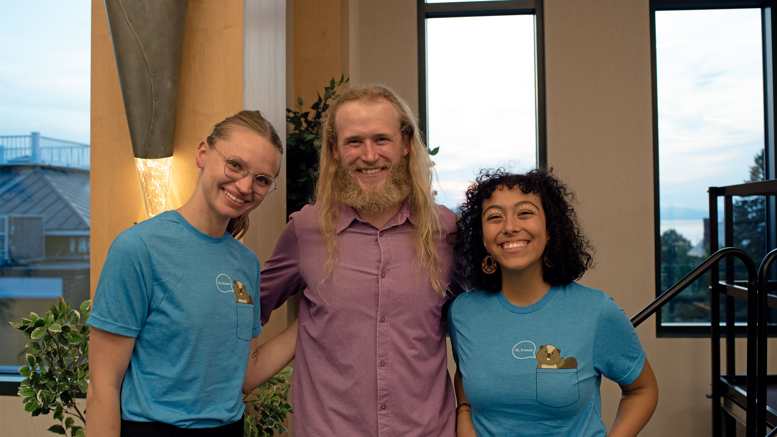 two students wearing blue dare to care t-shirts pose for a photo with drew petersen, wellbeing week keynote speaker