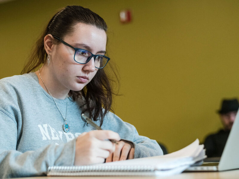 a student working on a laptop and writing in a notebook
