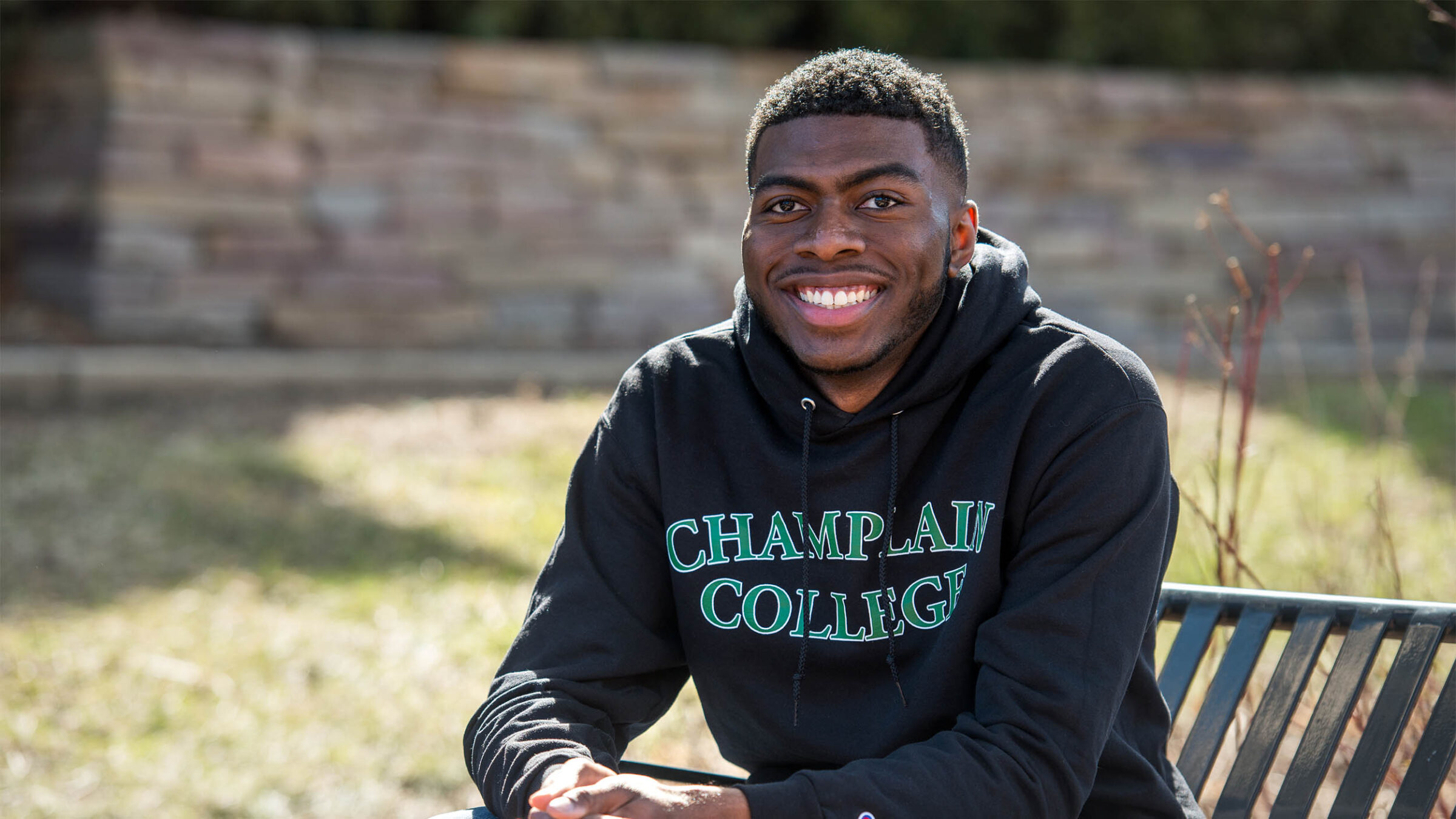 Anthony Mahon, class of 2019, sitting outside in a Champlain College hoddie