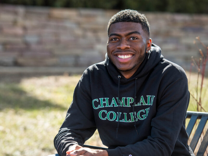 Anthony Mahon, class of 2019, sitting outside in a Champlain College hoddie