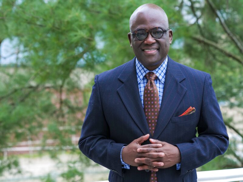 Former President Akande standing in front of foliage