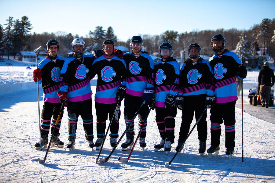 Champlain's Ice Hockey team wearing uniforms and helmets holding hockey sticks and standing in the ice rink together