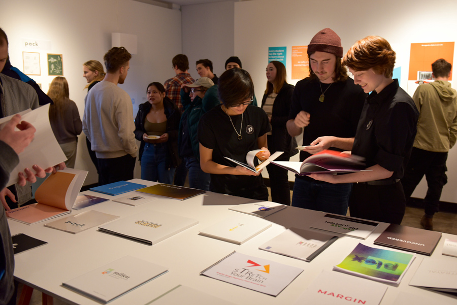 students looking through visual art, booklets, and printed materials in the Champlain Art Gallery