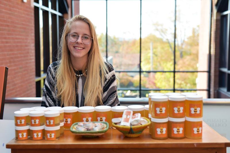 a student sitting behind a table of honey