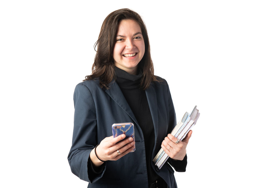 a student holding a cell phone and a pile of notebooks in front of a white background
