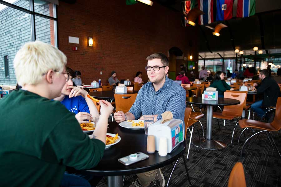 students eating lunch in IDX, sitting at round tables with flags overhead