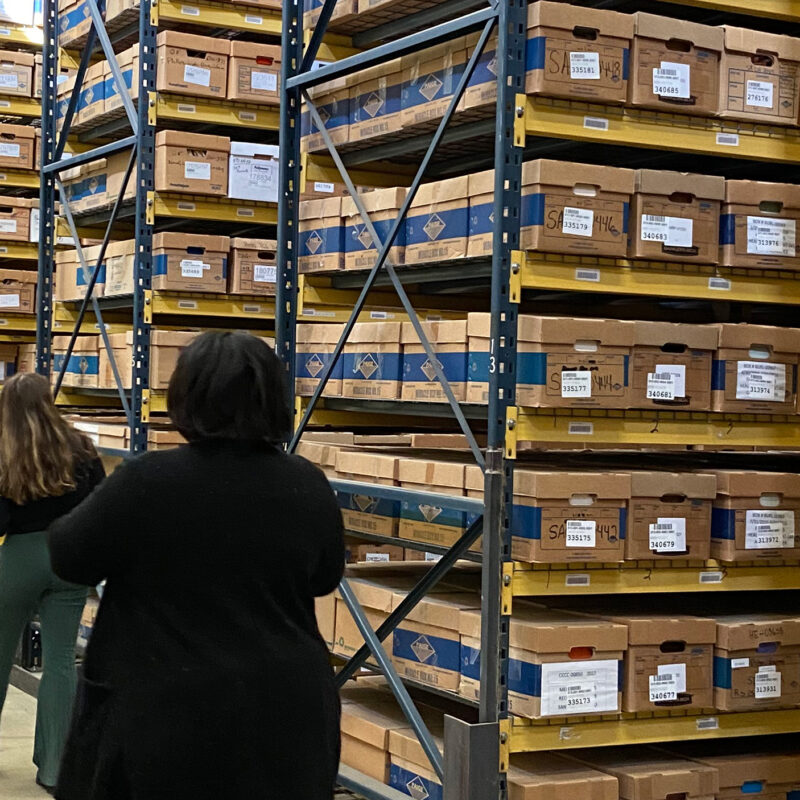 Professor and student walking through stacks of archive boxes