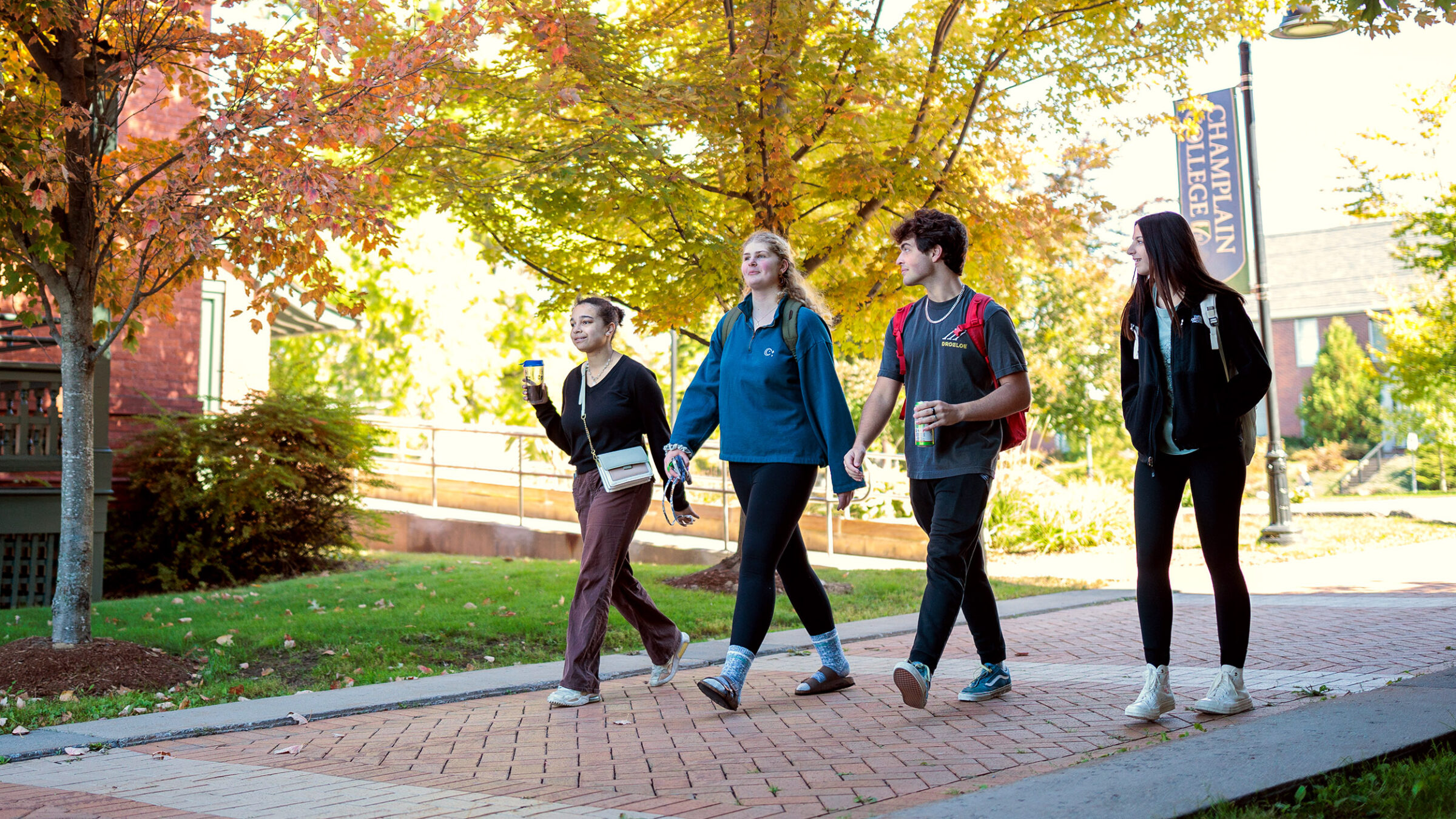 small group of students walk across campus on a sunny fall day