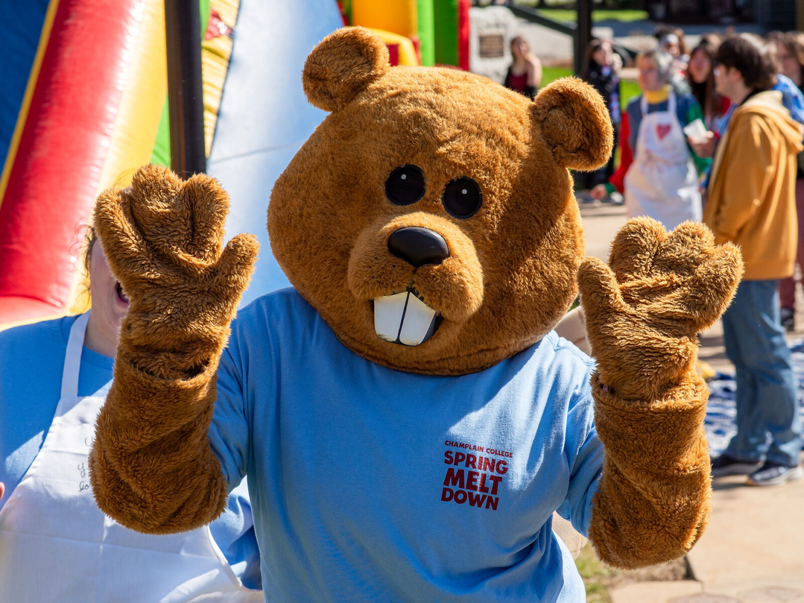 chauncey the beaver mascot holds both hands up in excitement with a big inflatable obstacle course behind him