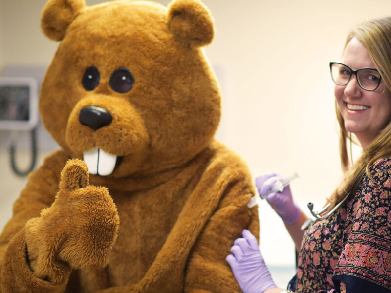 A nurse giving Chauncey a flu shot in the student health center clinic