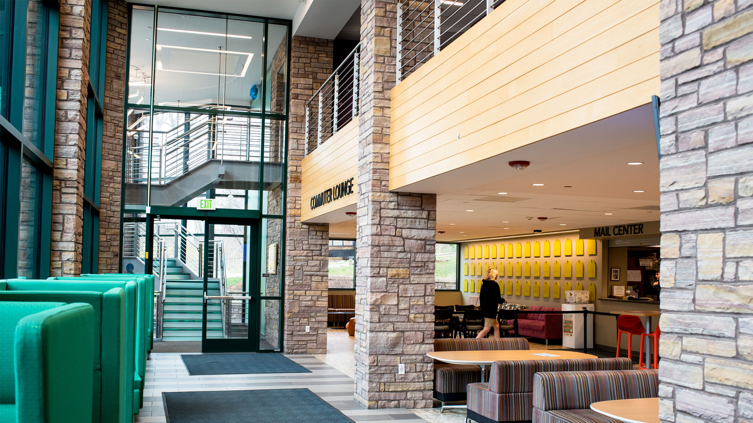 commuter lounge with big green chairs, comfy couches, tables, and the mail center