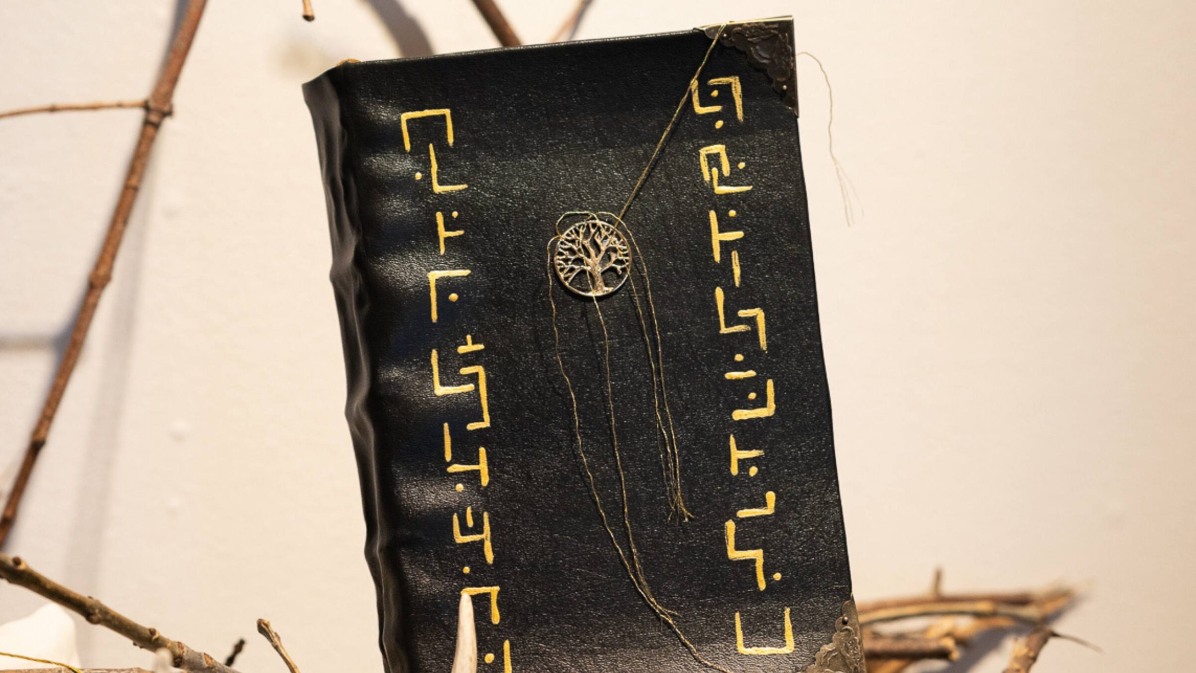 a leather bound book made by a creative media student positioned among tree branches and antlers