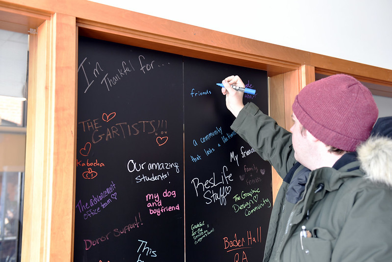 student writing on a black board with a liquid chalk pen
