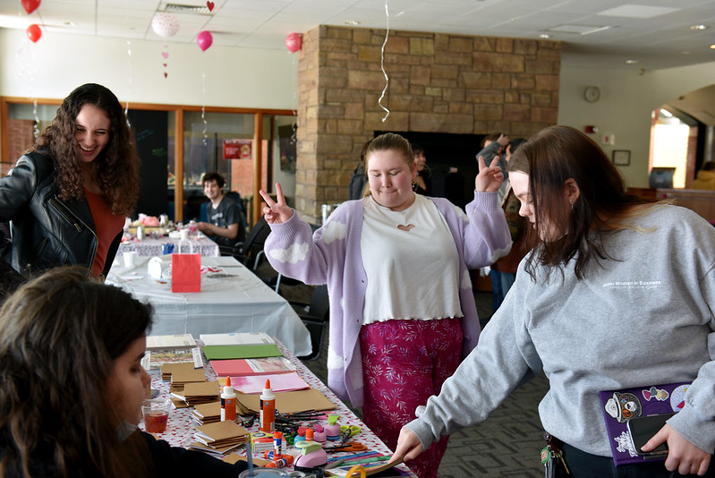 students dancing while looking at a table of office supplies at a campus event