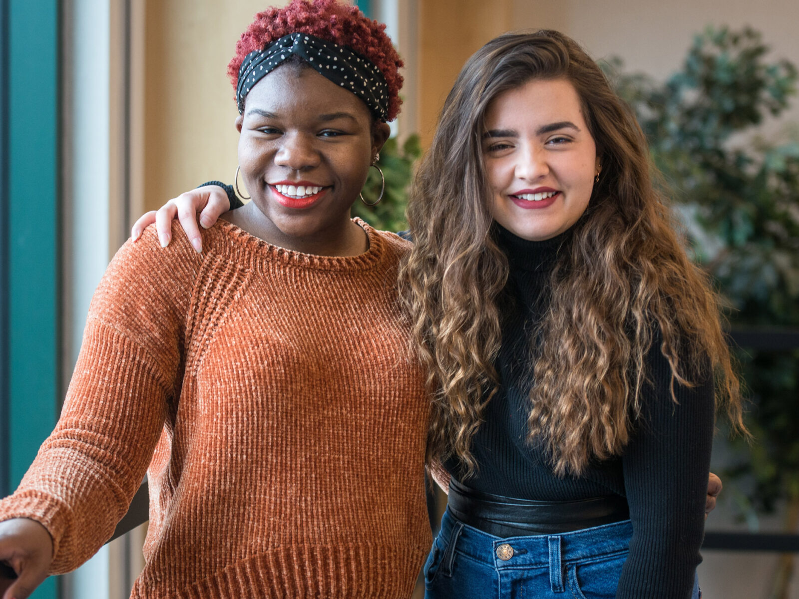 students with arms around one another smile at the camera