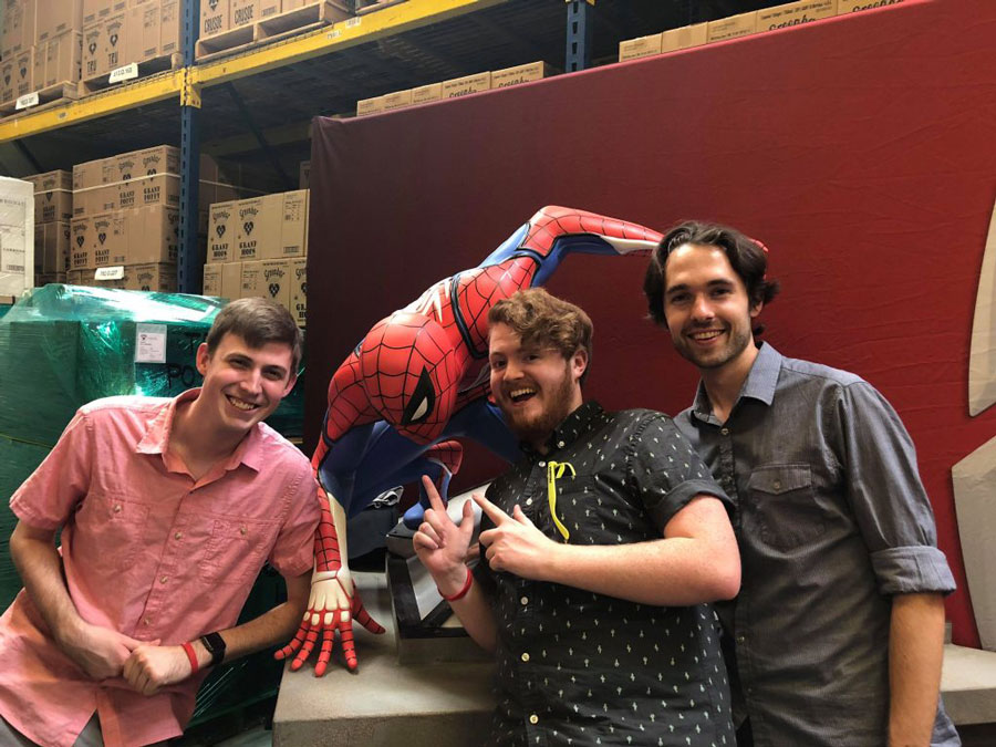 three game students posing next to a statue of spider man