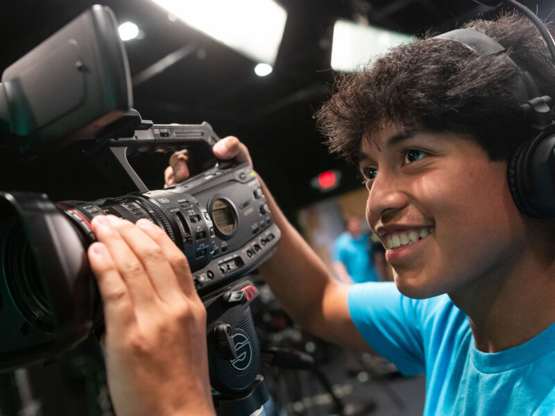 A high-school-aged student uses a camera at Champlain's pre-college summer program