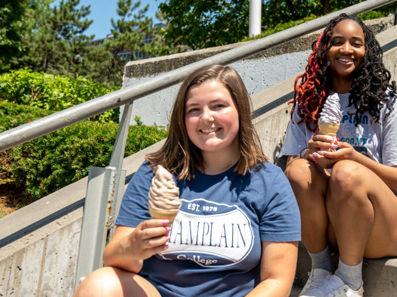 two students sit on stairs outside eating ice cream cones