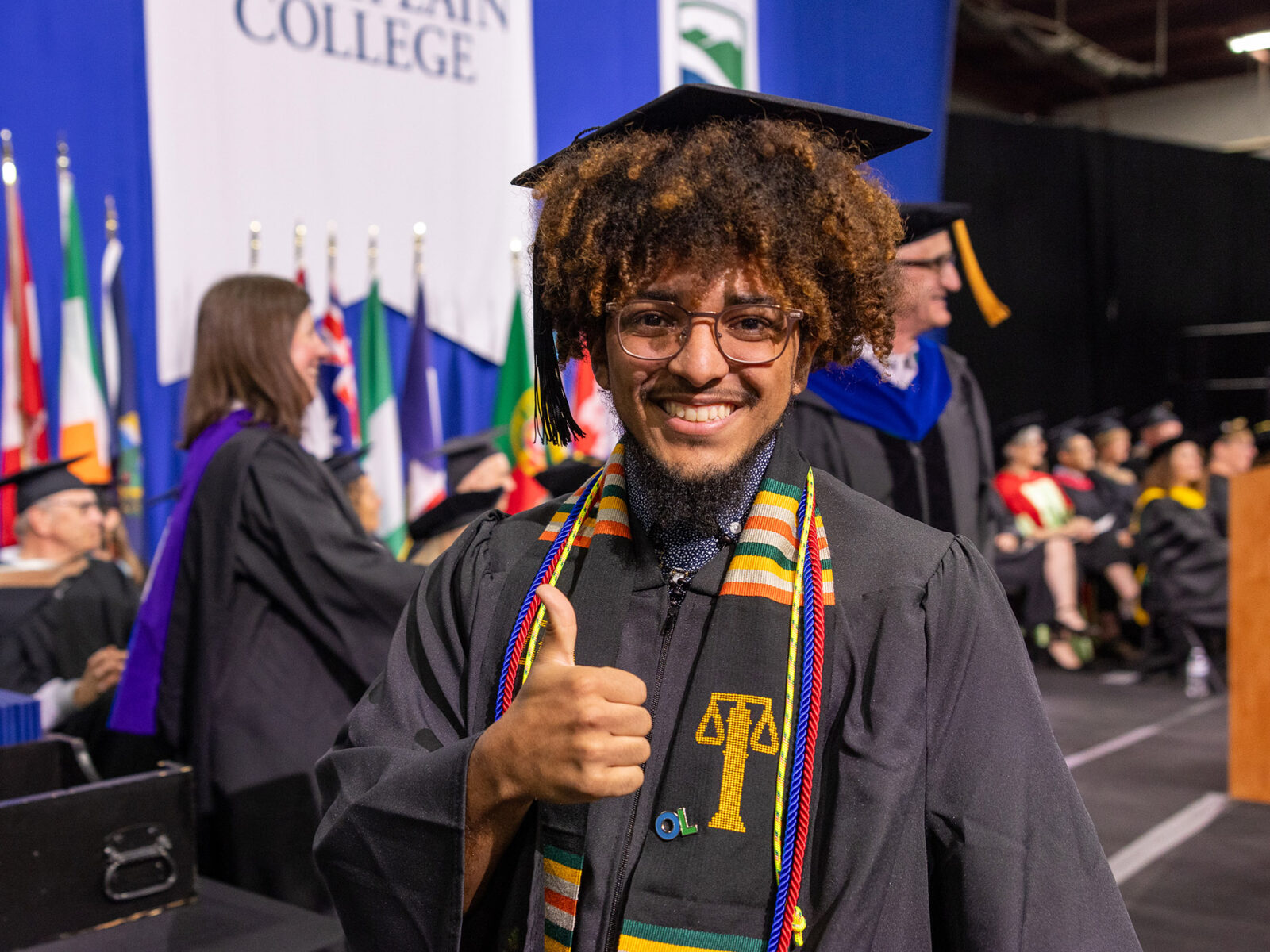 new graduate gives the camera a thumbs up and a smile