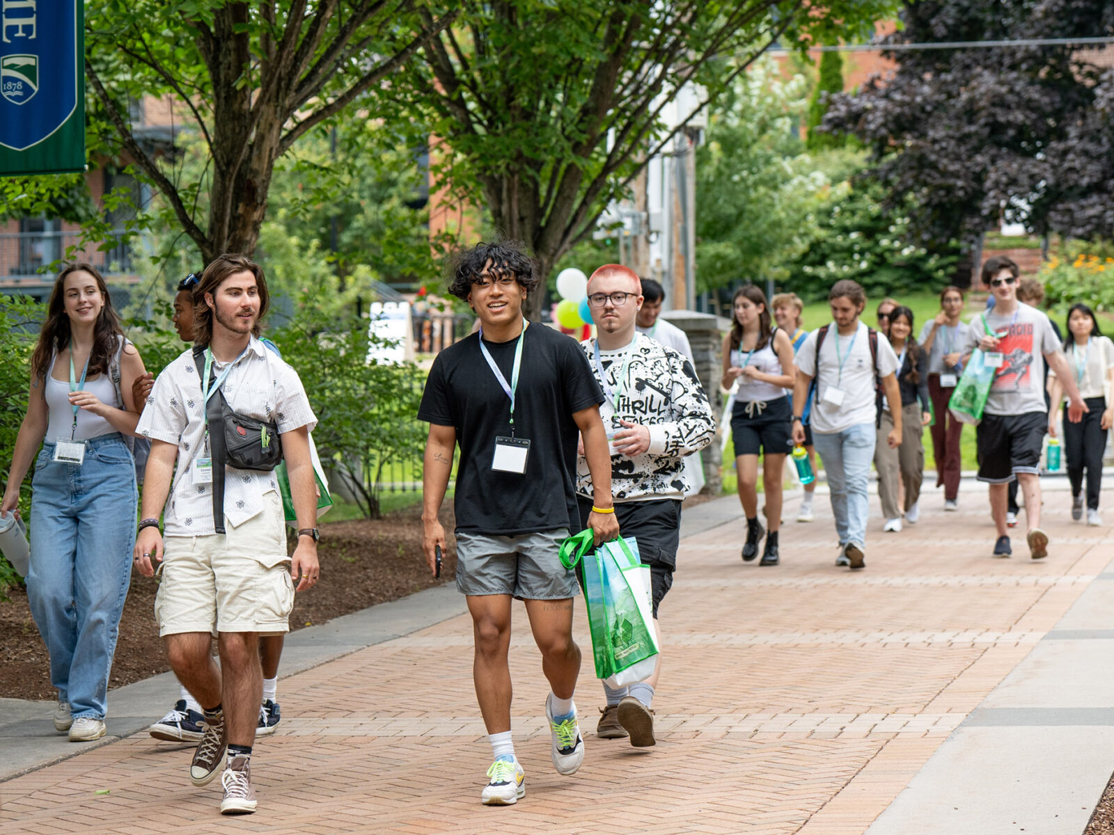 large group of students walk across campus