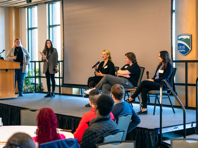 Mackenzie Marsocci ’20, Emily Platz ’20, and Samantha Moench ’17 on stage at the Women in Cyber Summit