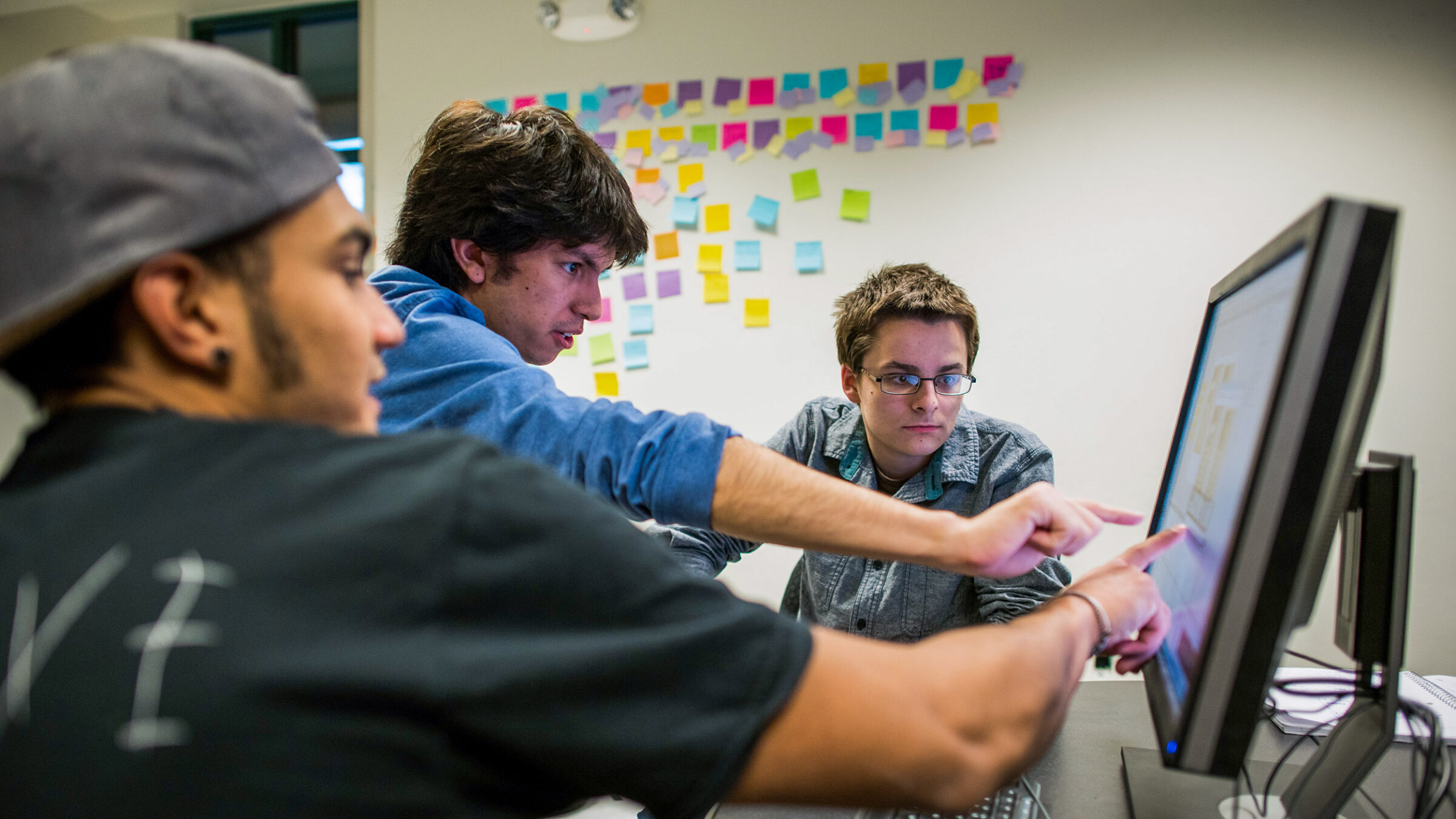 students collaborate pointing at a computer