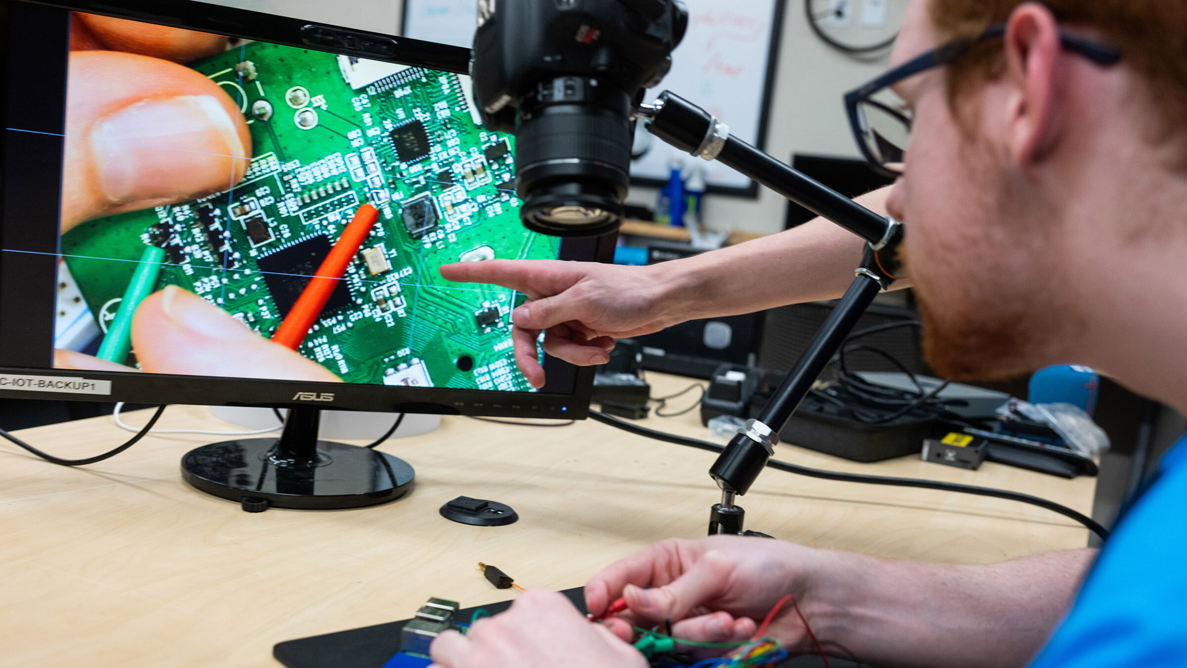 student works on computer hardware, a camera magnifies the work on a computer screen for easier work