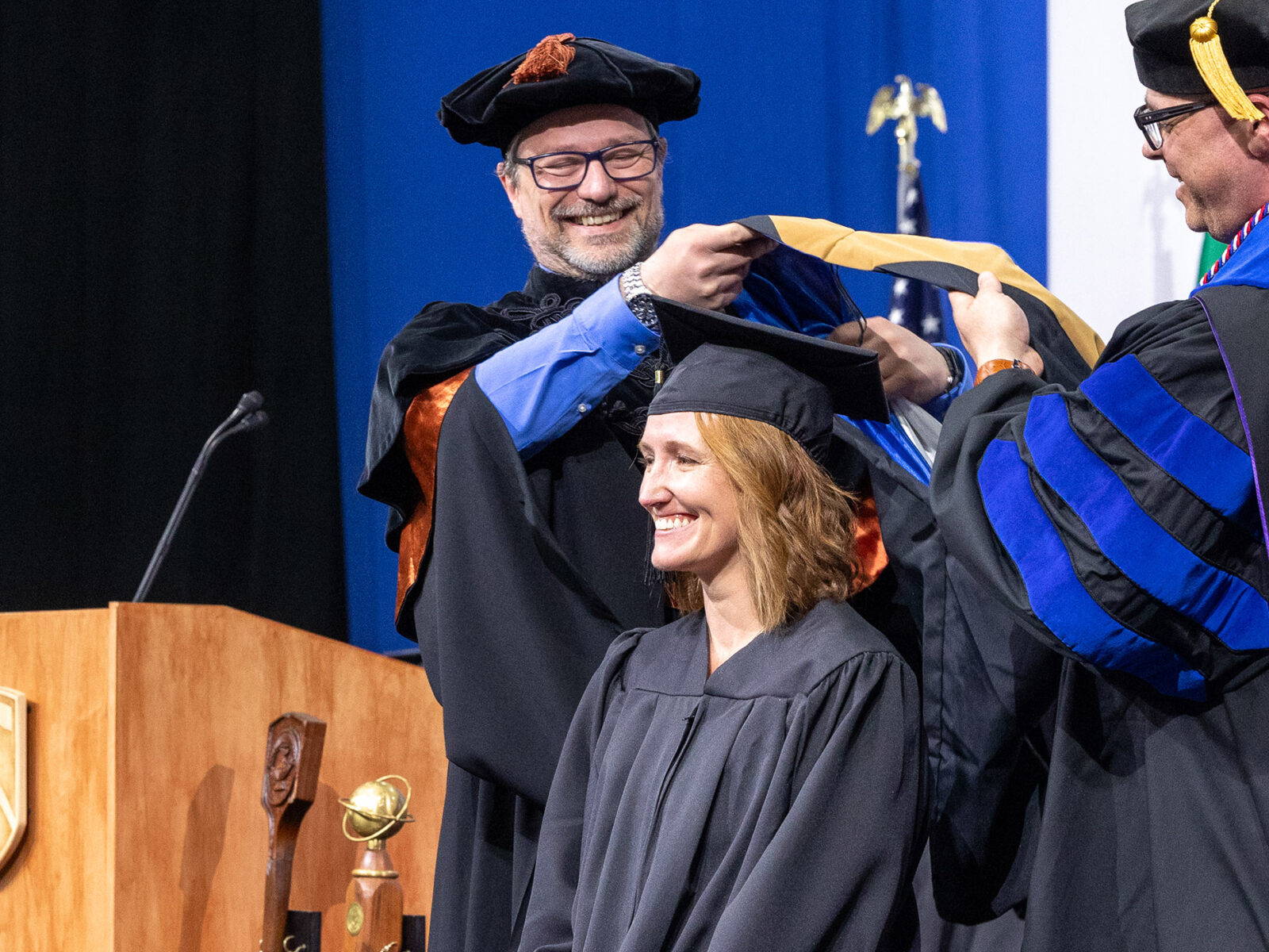 cco masters student smiles being awarded their hood at commencement