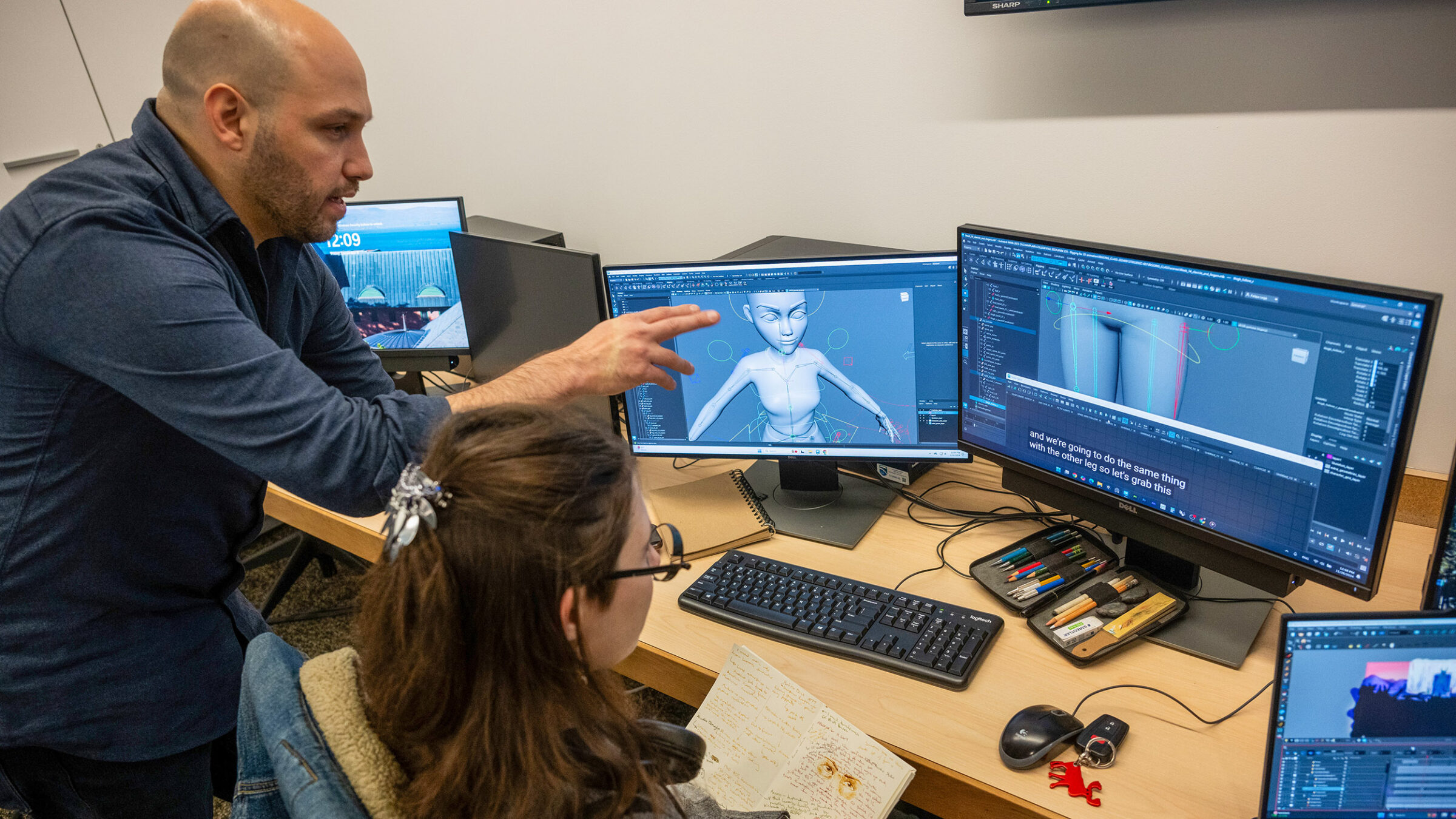 a student getting advice from a professor while working on digital animation