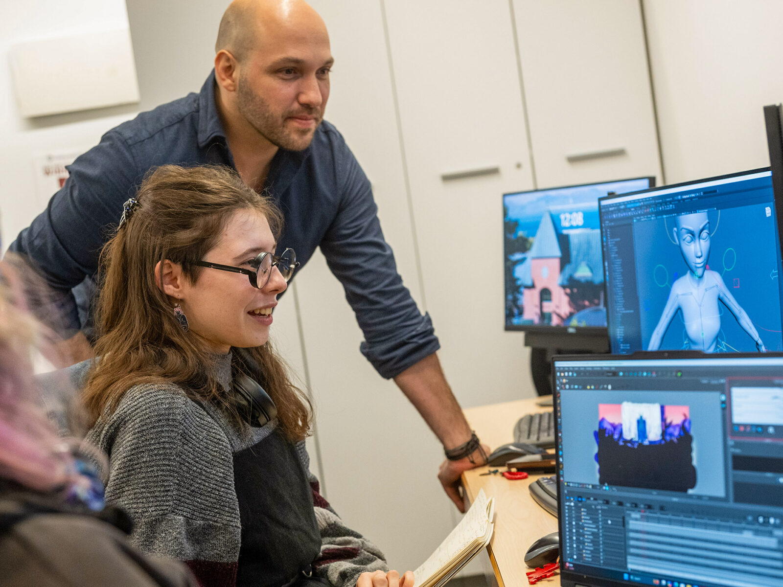 a student working on animation while a professor assists