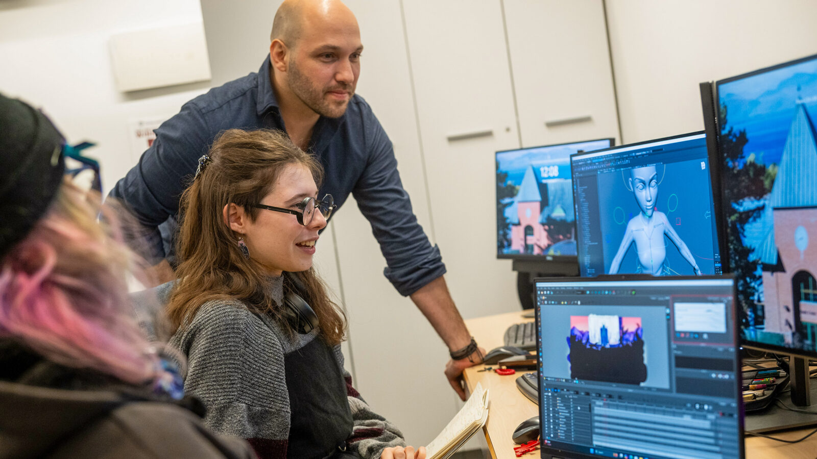 a student working on animation while a professor assists
