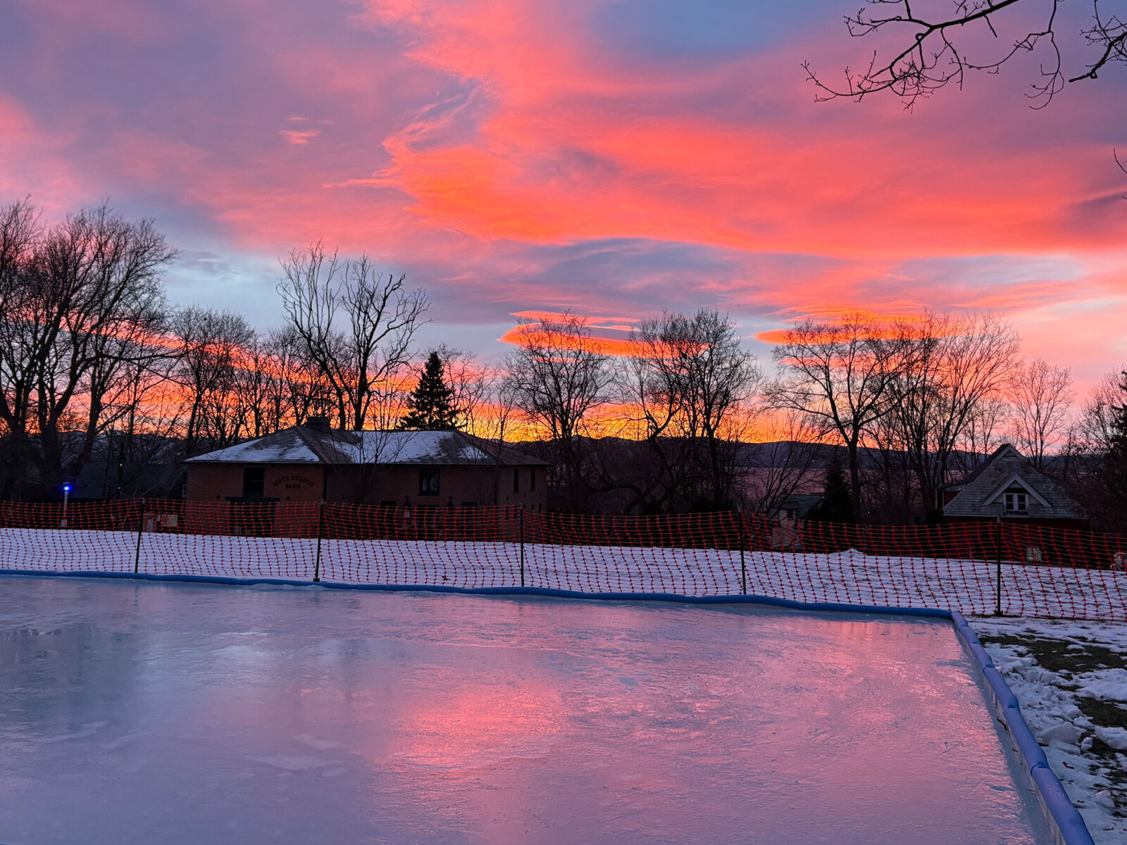 ice rink on campus on perry hall lawn with a pink and orange sunset in the background