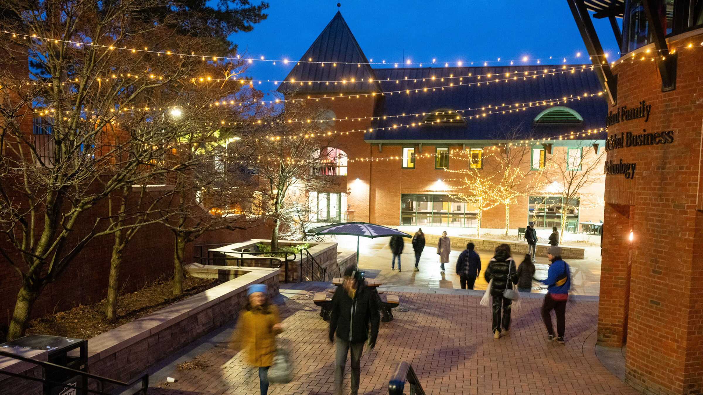 Christmas lights hanging over campus courtyard while students walk to class