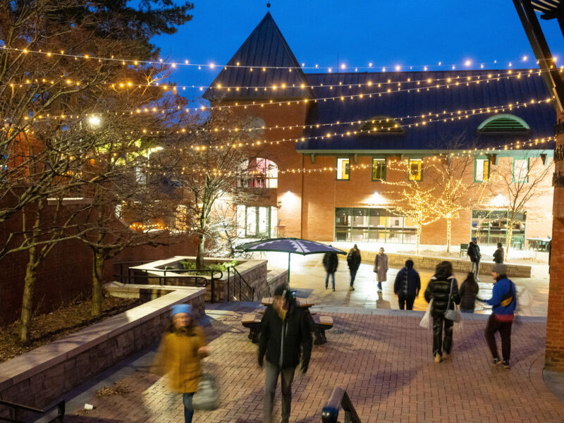 Christmas lights hanging over campus courtyard while students walk to class