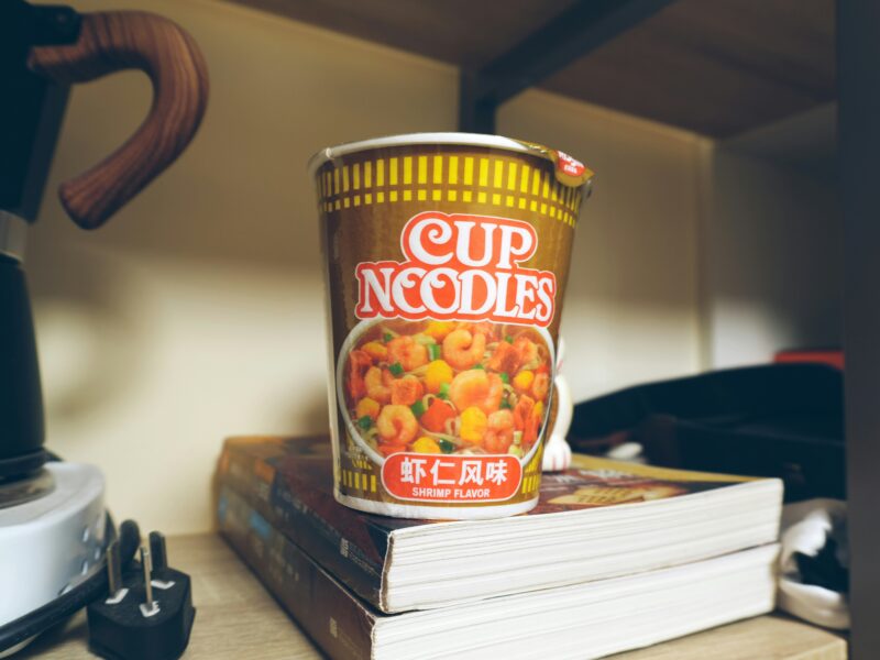 cup of ramen noodles placed on stack of books