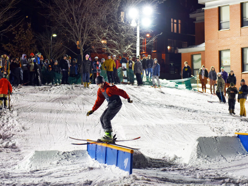 skiier rides on a ramp in finney quad with a large group of people watching